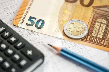 Banknot 50 euro, moneta 2 euro, kalkulator i ołówek na dokumentach finansowych.